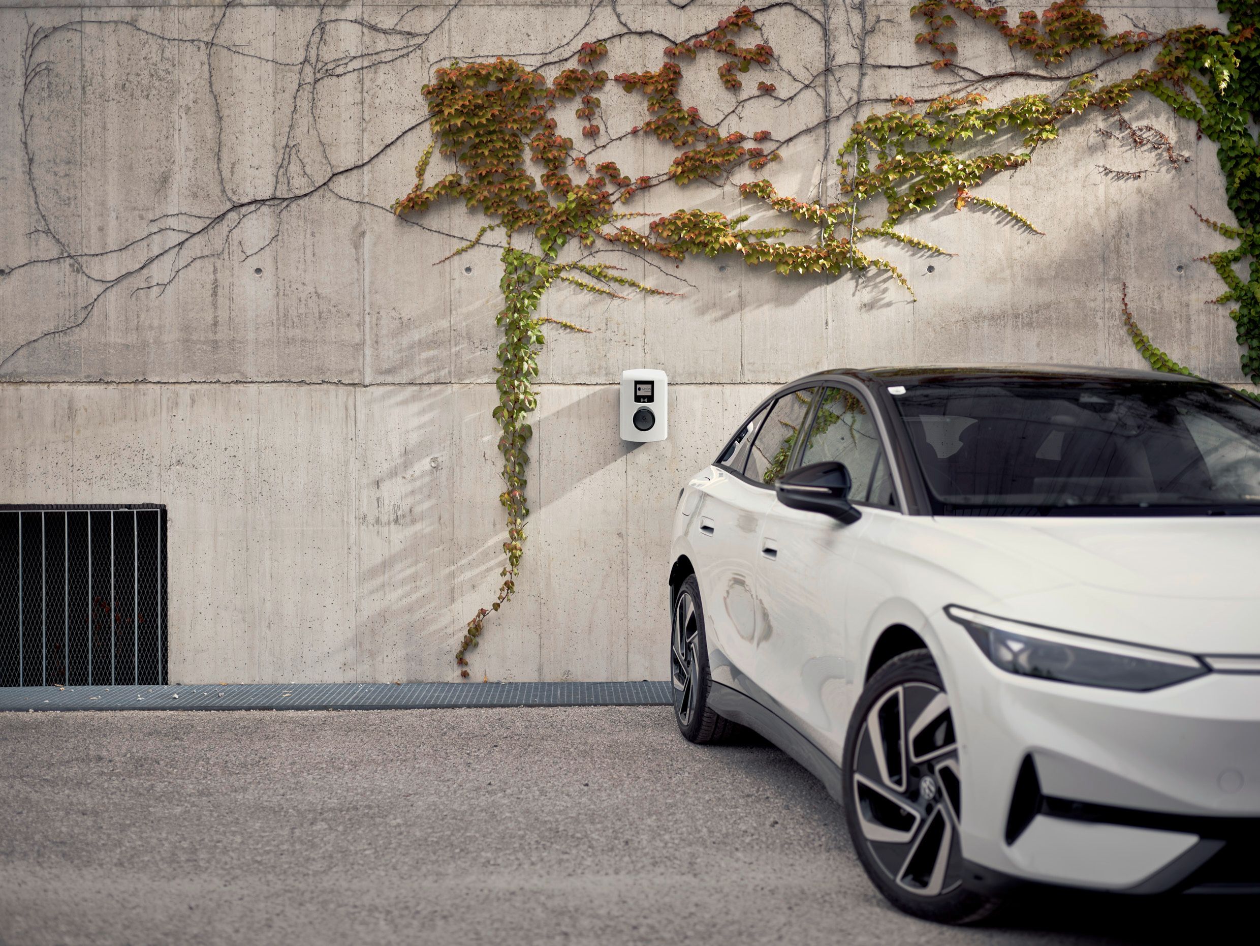 Auto steht vor einer Betonwand mit Wallbox