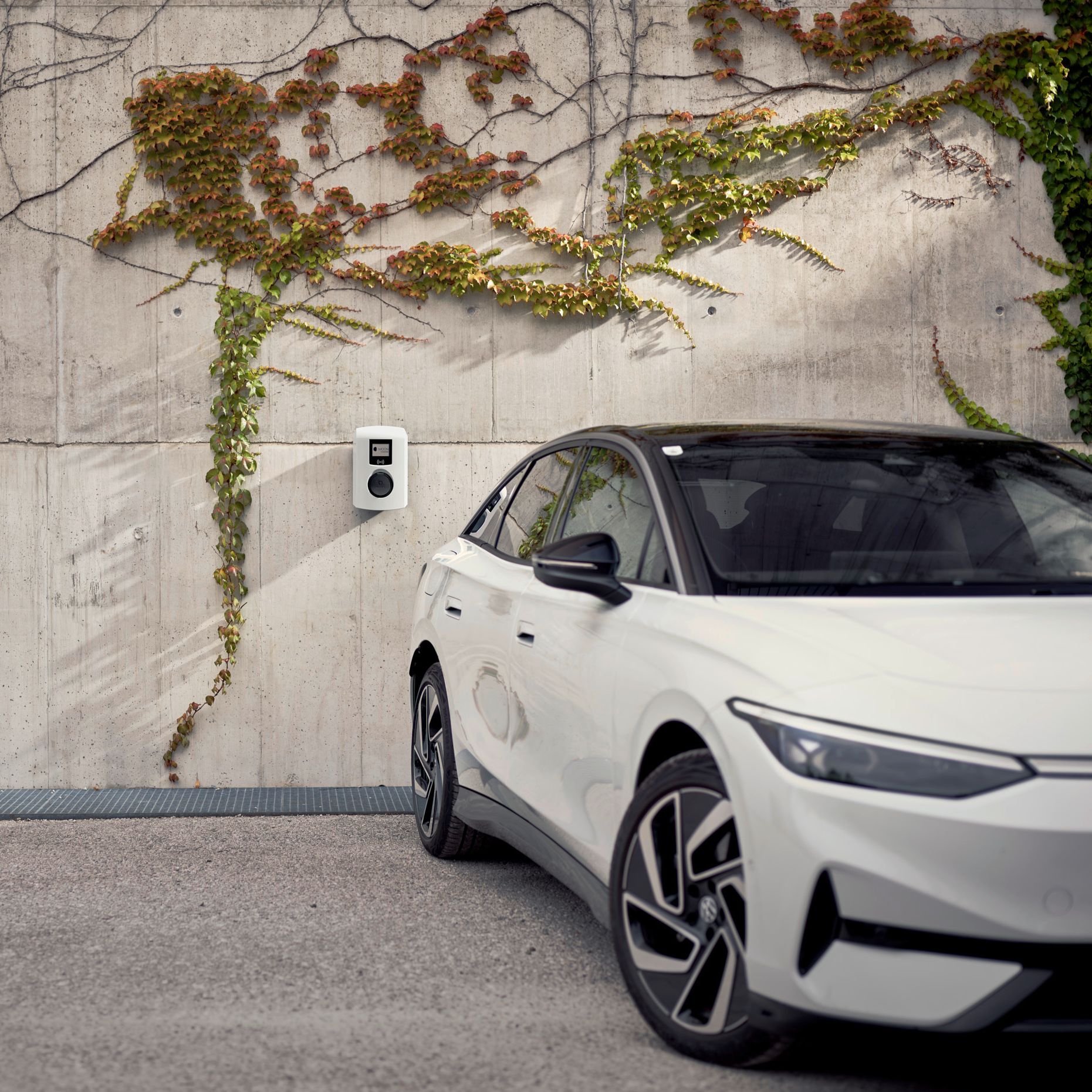 E-Auto steht vor einer Betonwand mit Wallbox