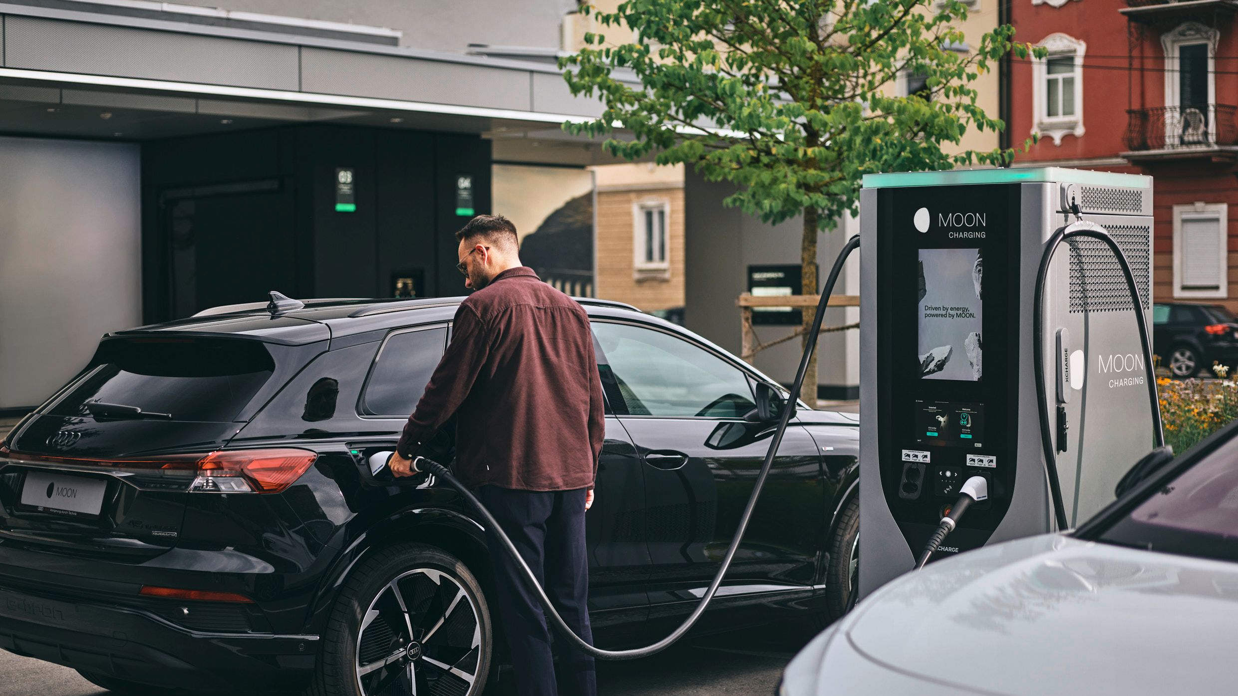 Person lädt Auto an Ladestation