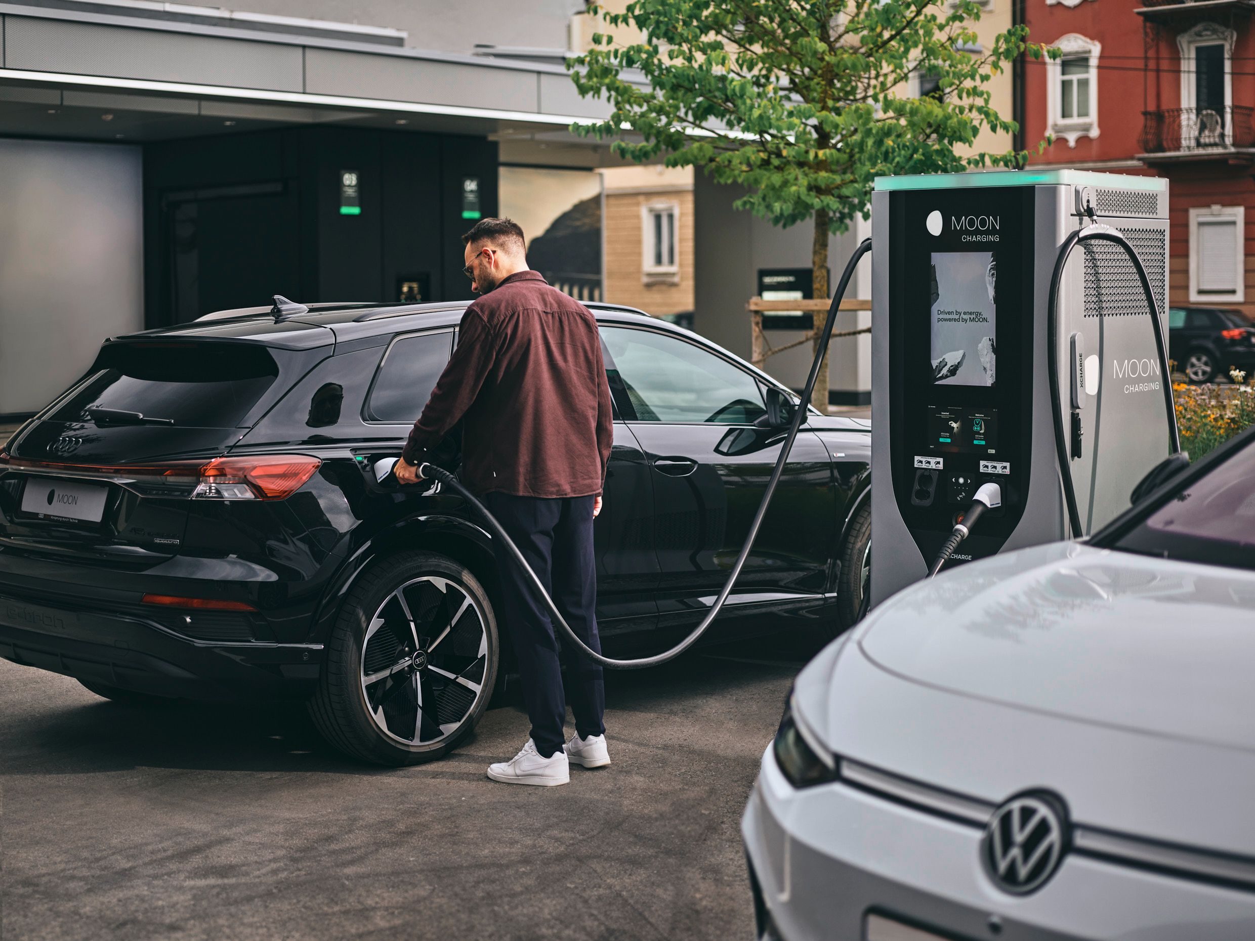 Person lädt Auto an Ladestation