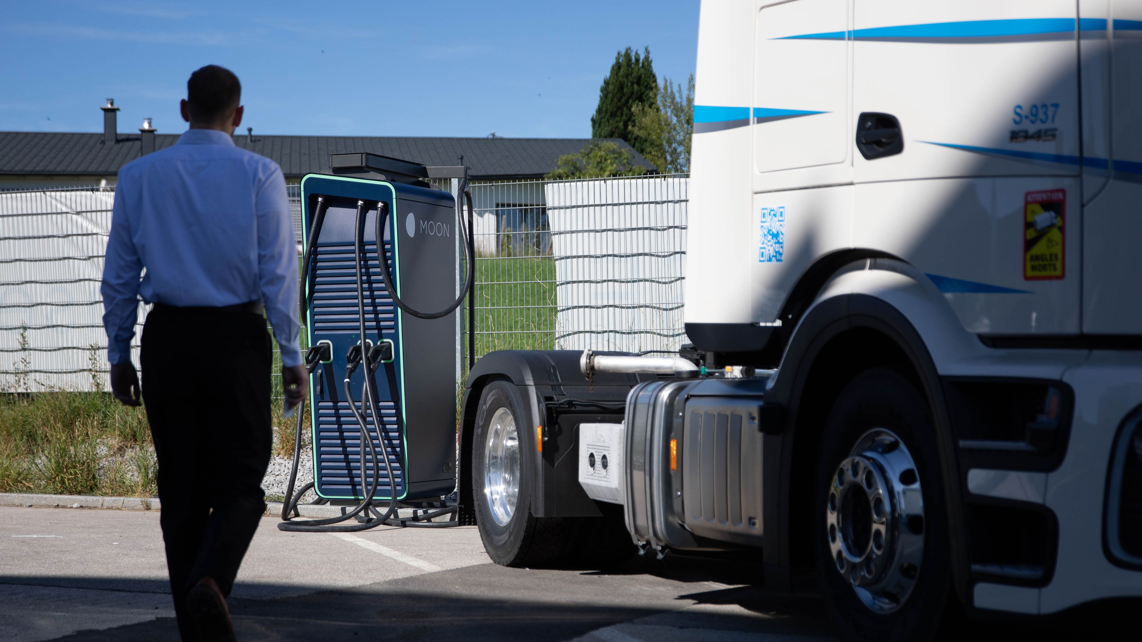 ein Mann geht zu einer HYC 200-400 Schnelladestation neben einem LKW