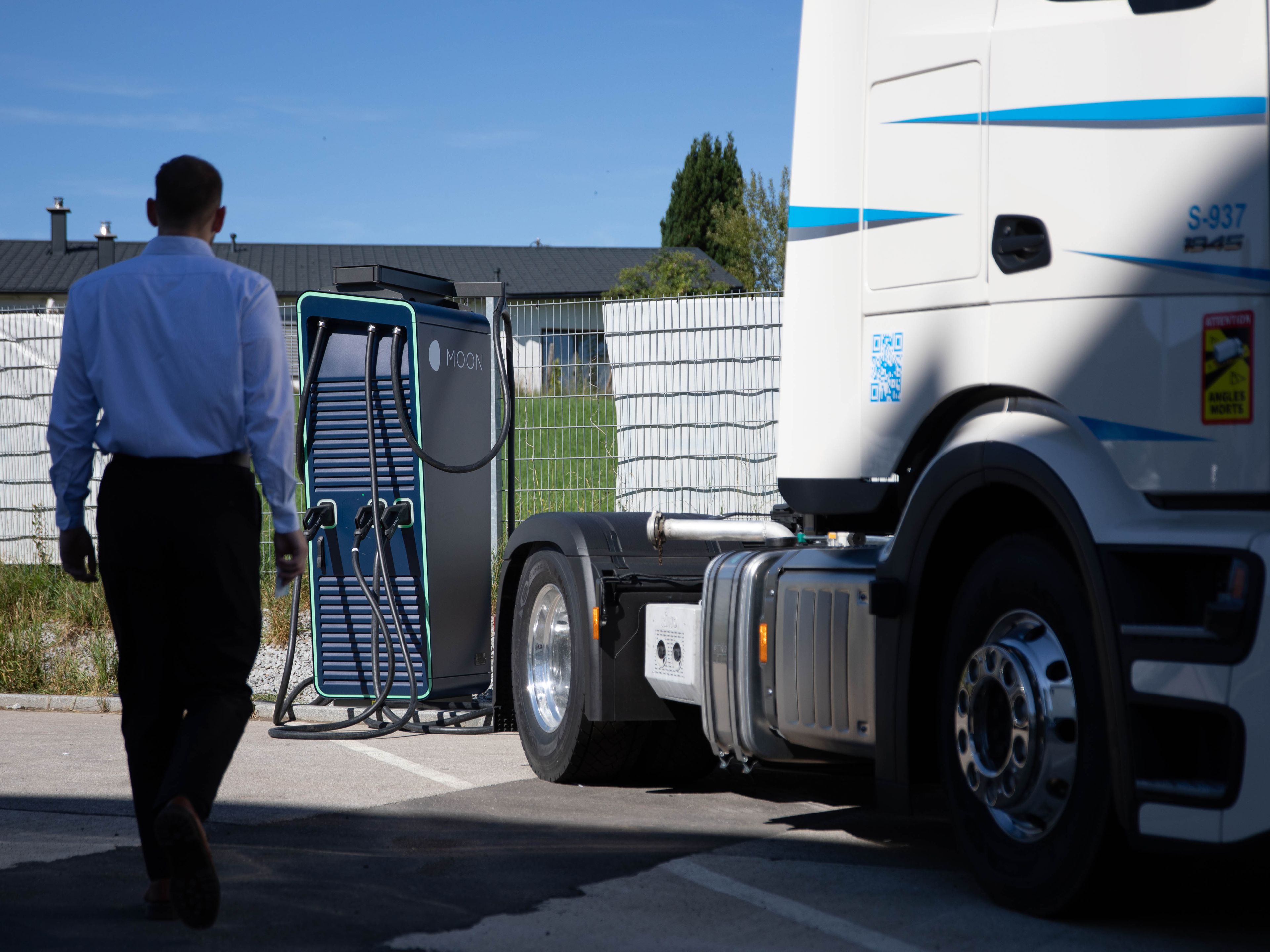 ein Mann geht zu einer HYC 200-400 Schnelladestation neben einem LKW