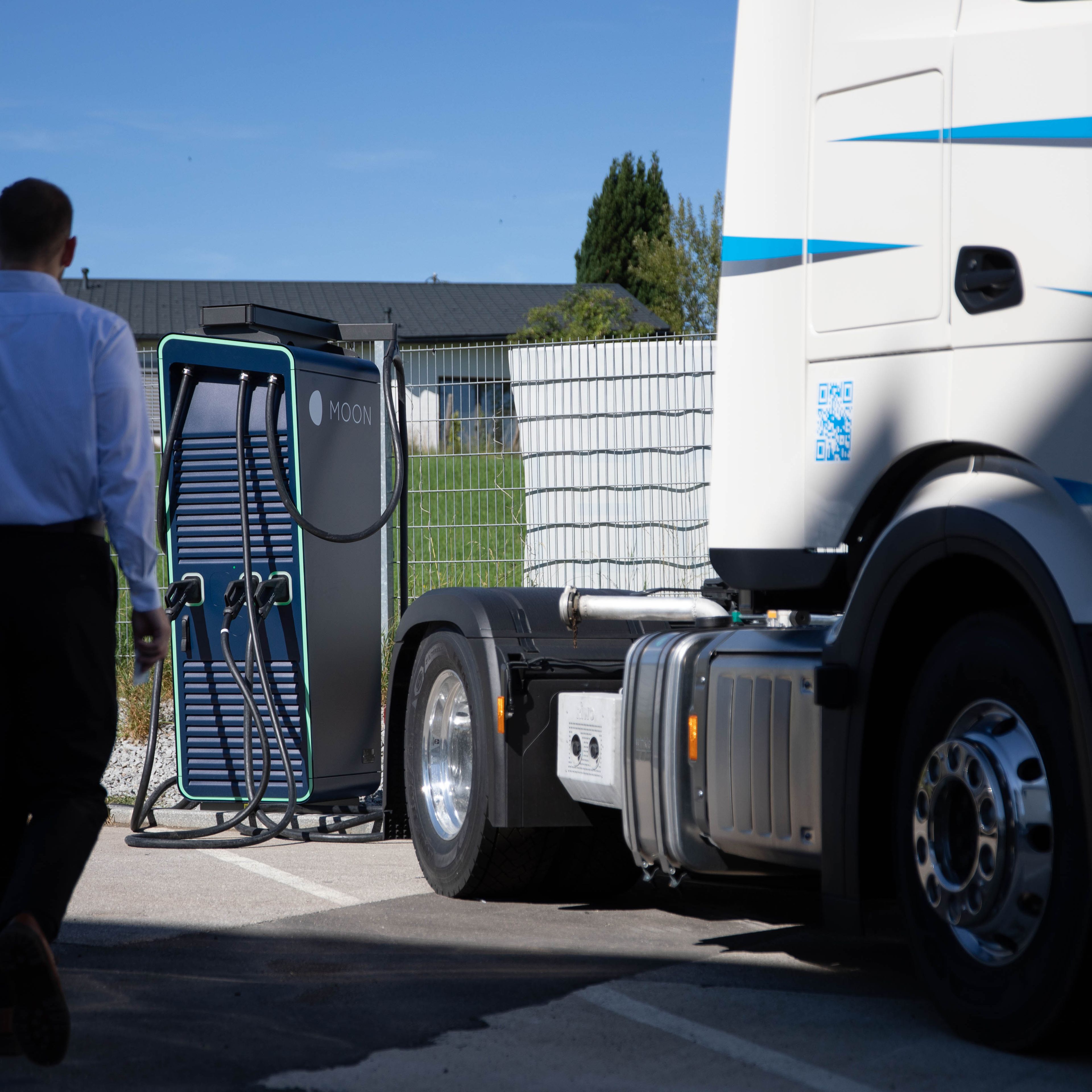 ein Mann geht zu einer HYC 200-400 Schnelladestation neben einem LKW