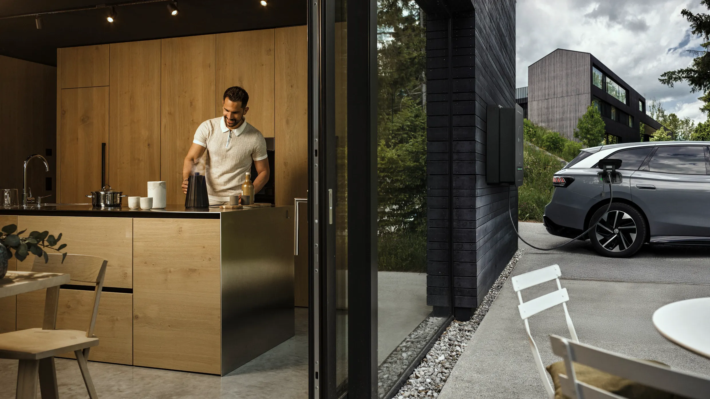 Mann in der Küche während Auto durch bidirektionale Wallbox Haus mit Strom versorgt