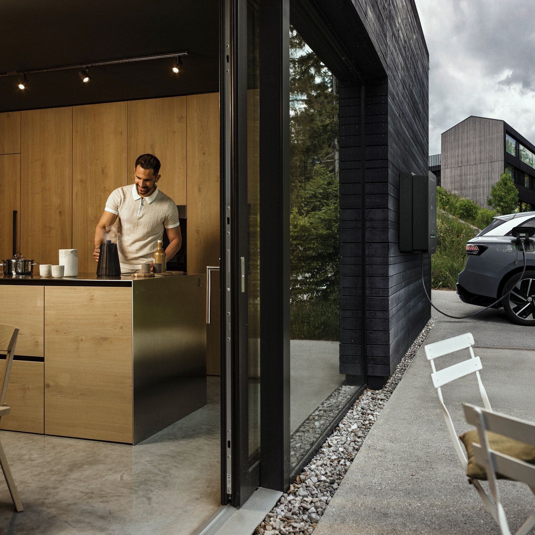 Mann in der Küche während Auto durch bidirektionale Wallbox Haus mit Strom versorgt