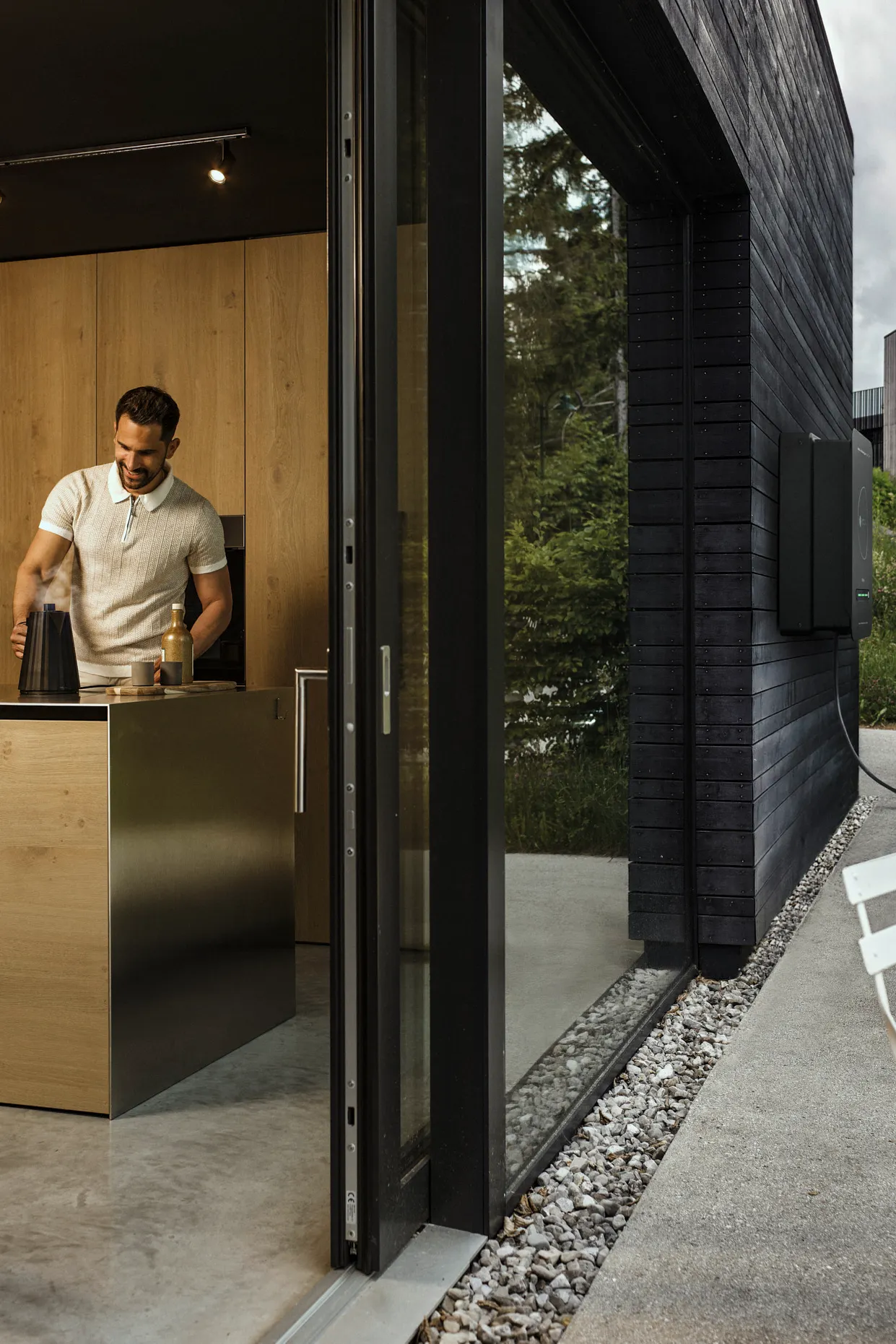 Mann in der Küche während Auto durch bidirektionale Wallbox Haus mit Strom versorgt