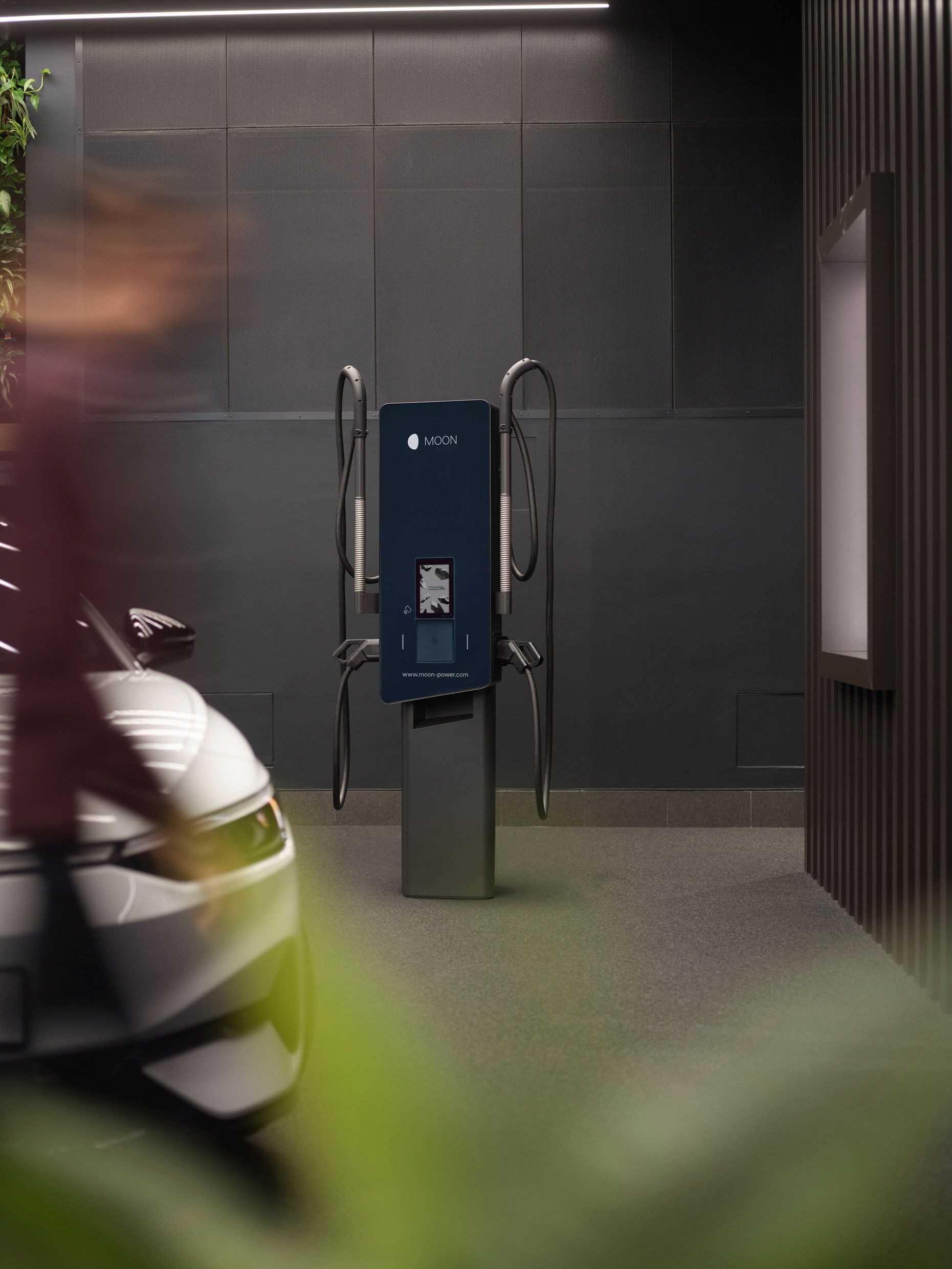 Wallbox in einem Raum mit grauen Wänden und einem E-Auto im Vordergrund