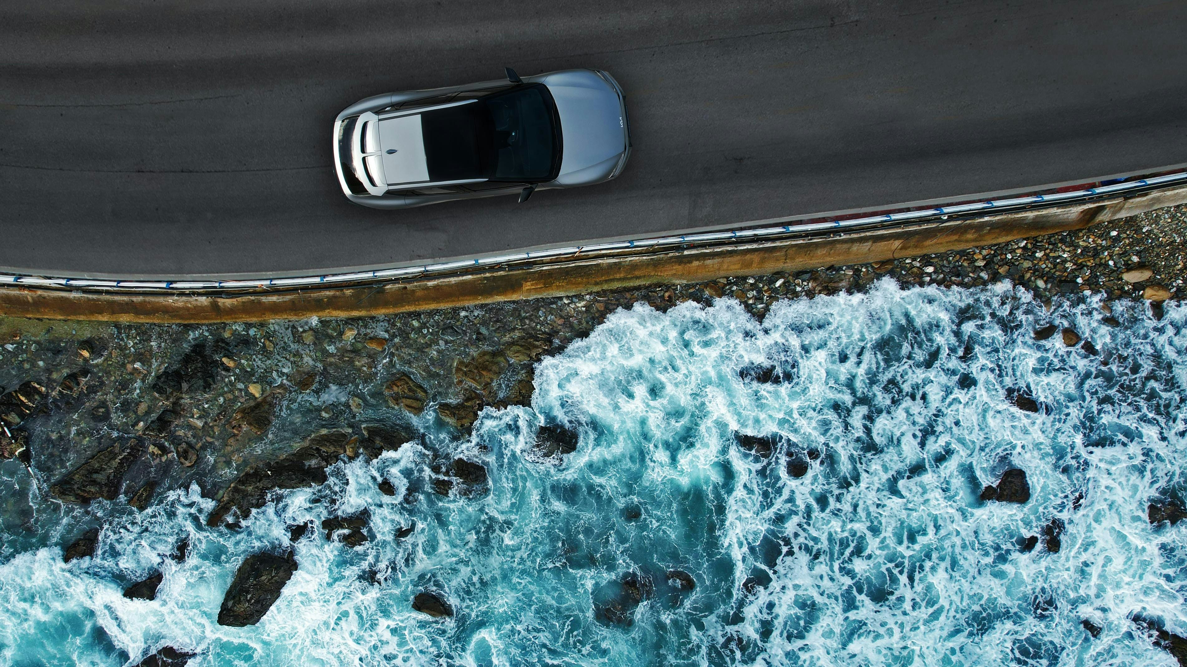 Luftaufnahme eines Autos, das am Meer entlangfährt 