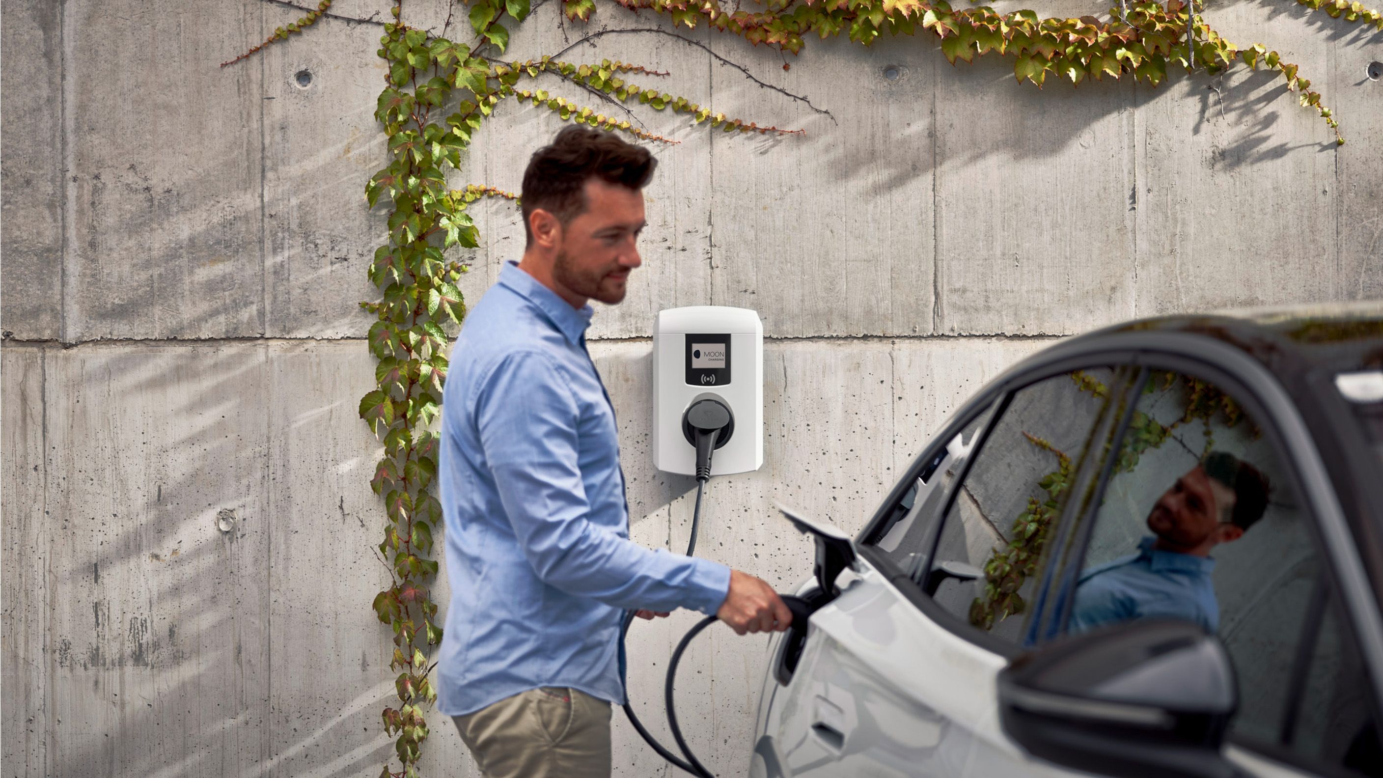 Mann lädt Auto mit einer Wallbox