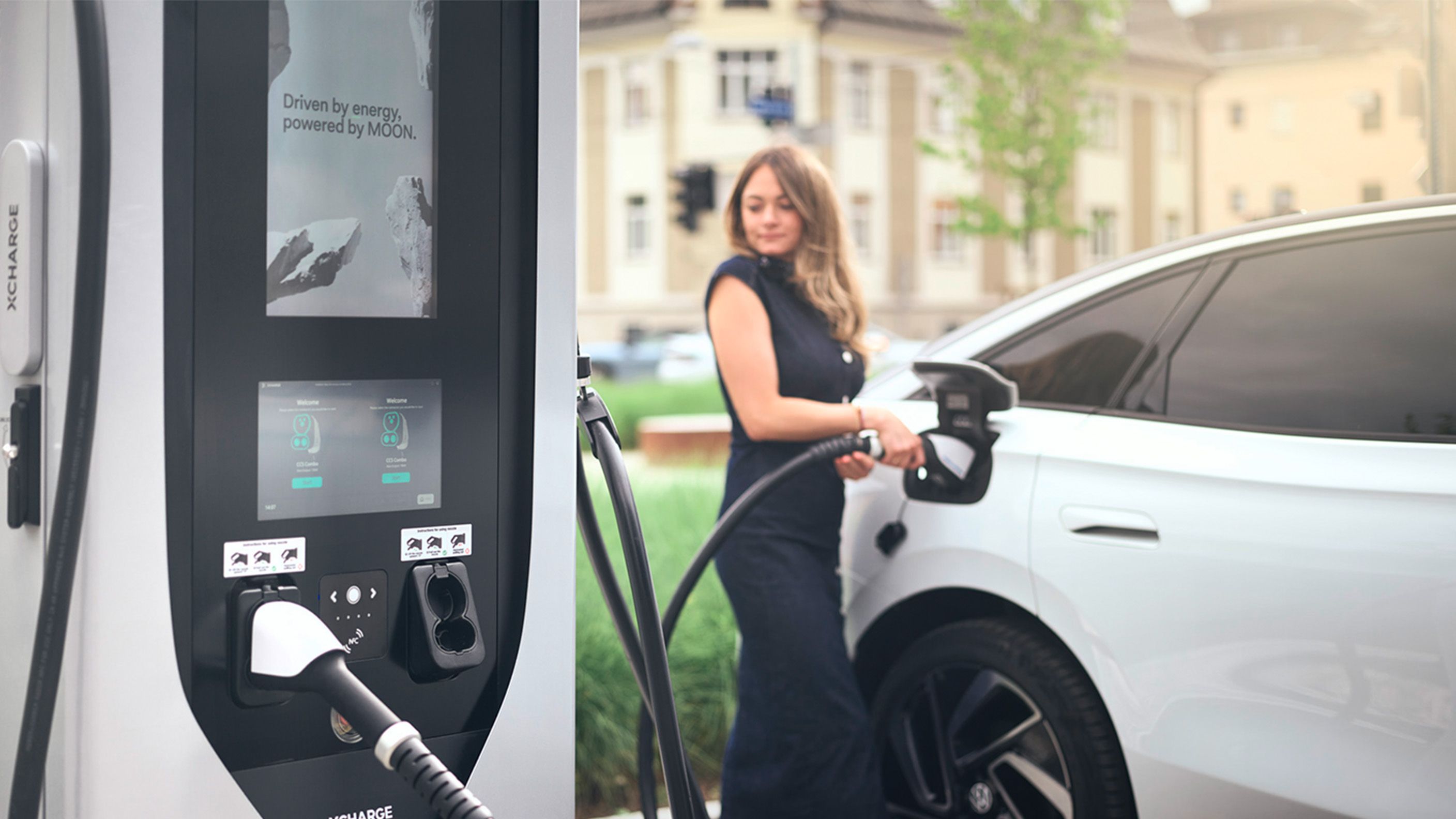 Frau lädt E-Auto mit einer Ladestation