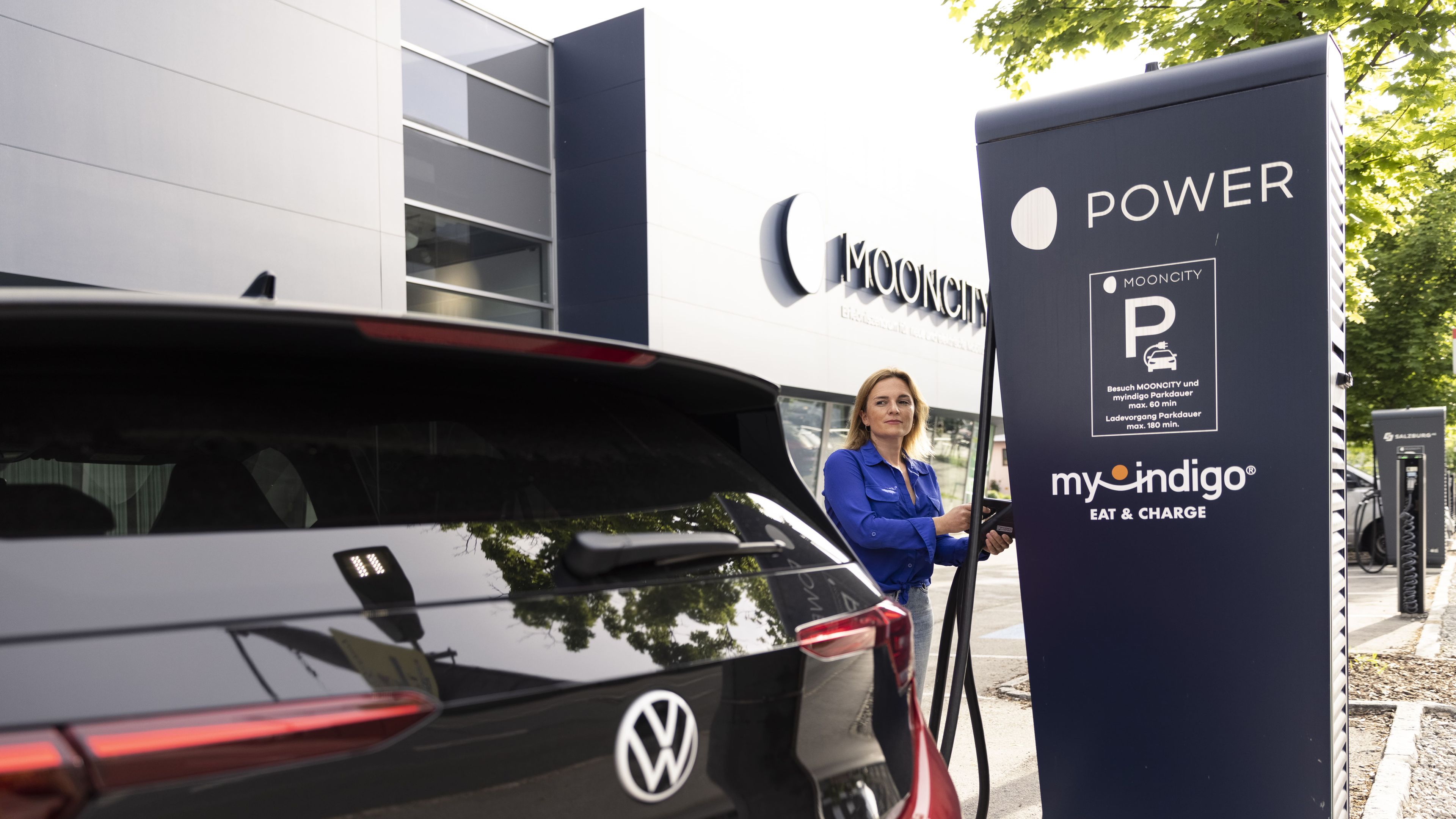 Romy Sigl lädt ID.3 an einem POWER Charger vor der MOONCITY
