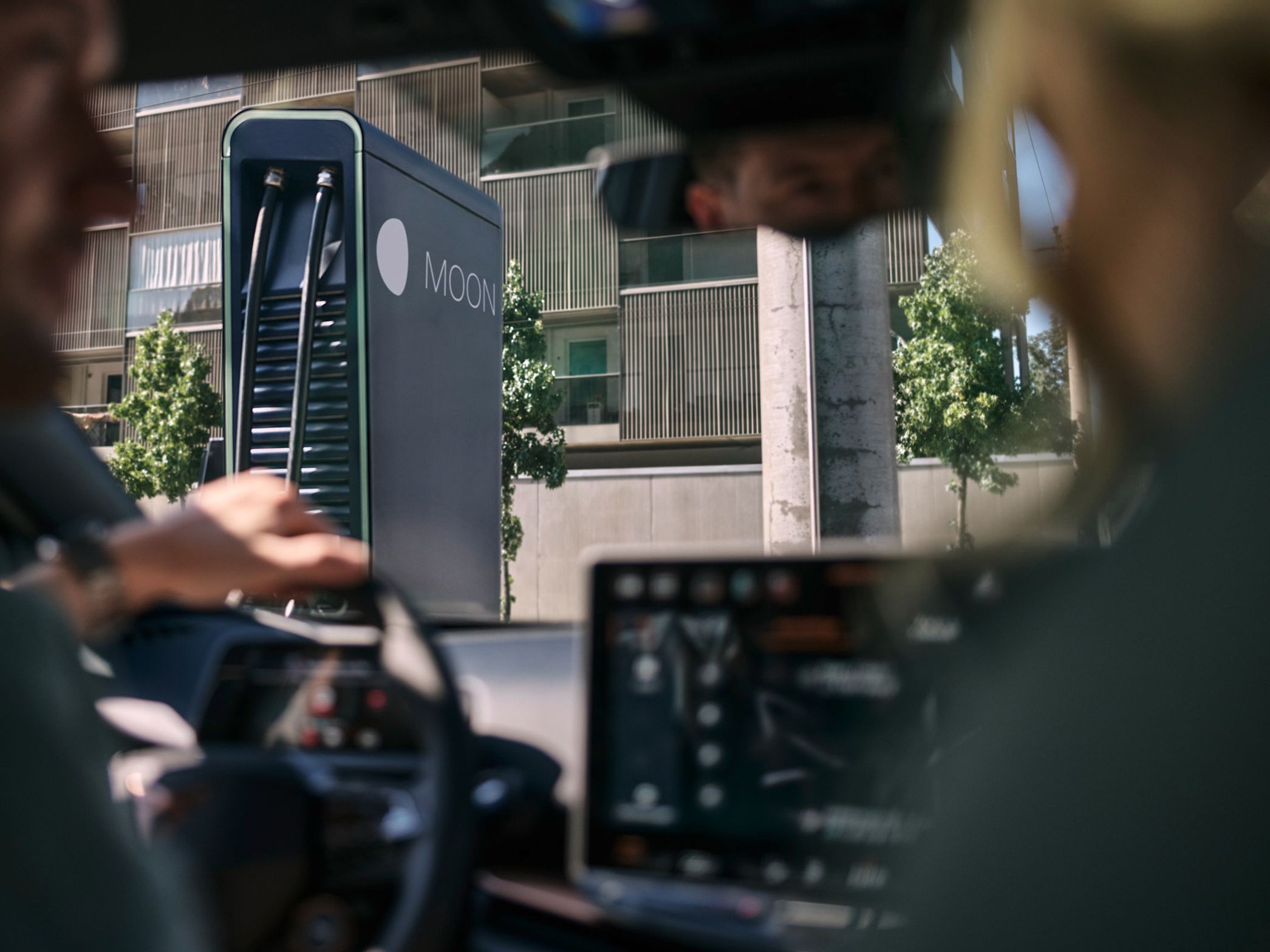 zwei Personen in einem E-Auto vor einer Schnellladestation