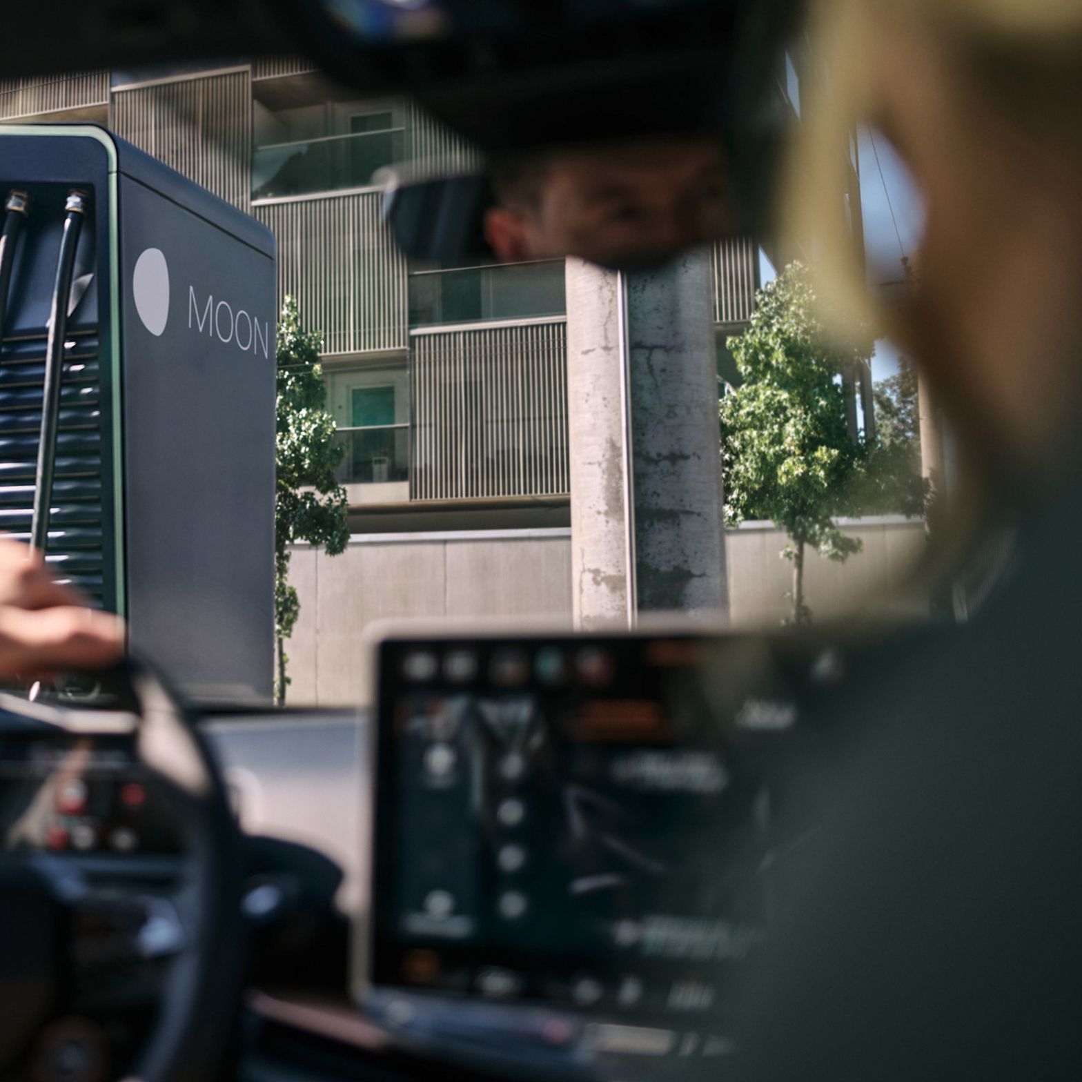 zwei Personen in einem E-Auto vor einer Schnellladestation