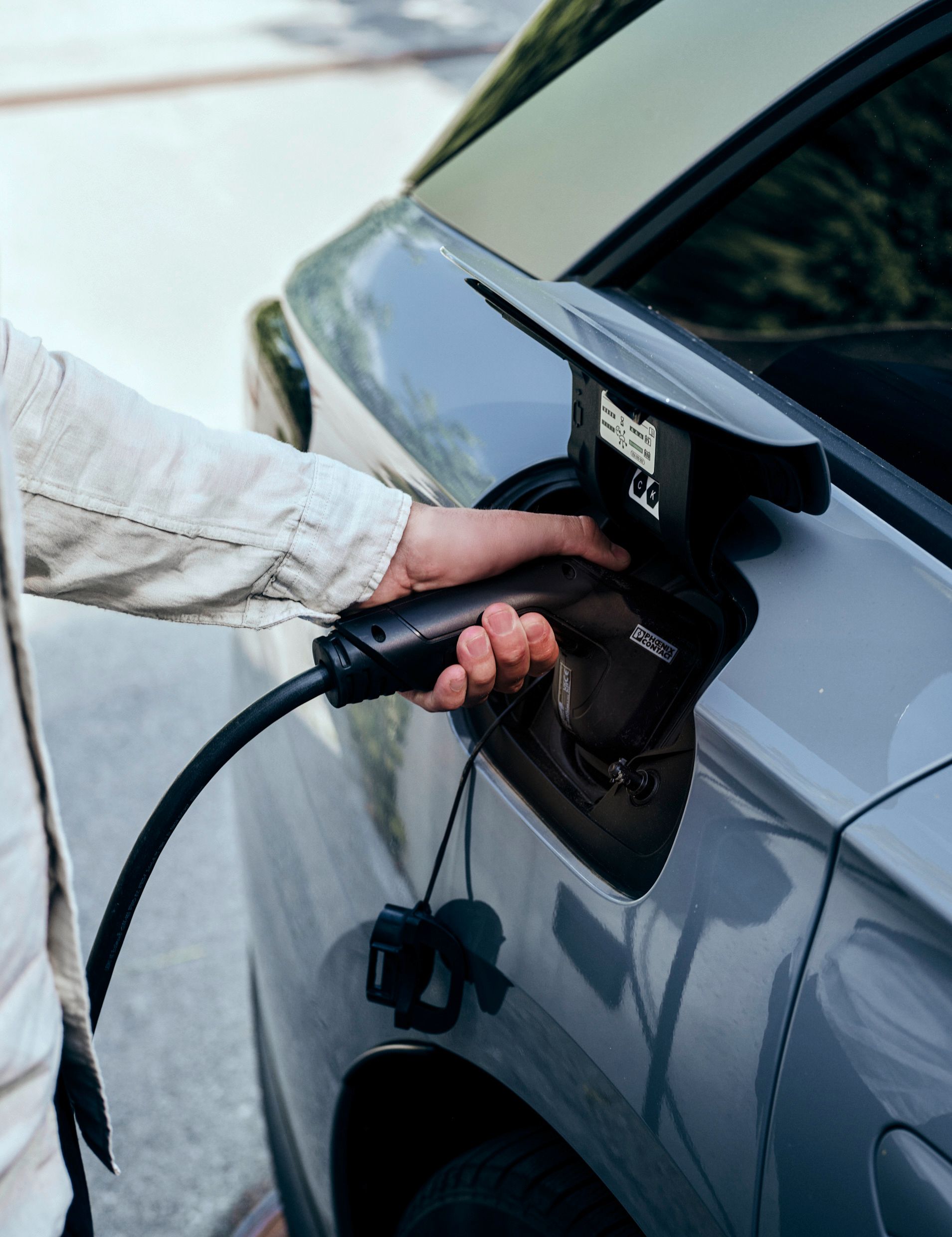 Mann steckt Kabel an E-Auto an