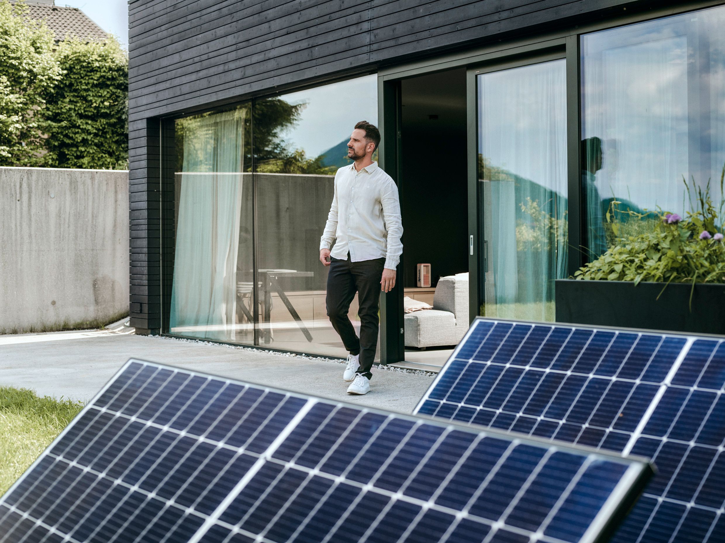 Mann vor Haus mit PV-Anlage im Vordergrund