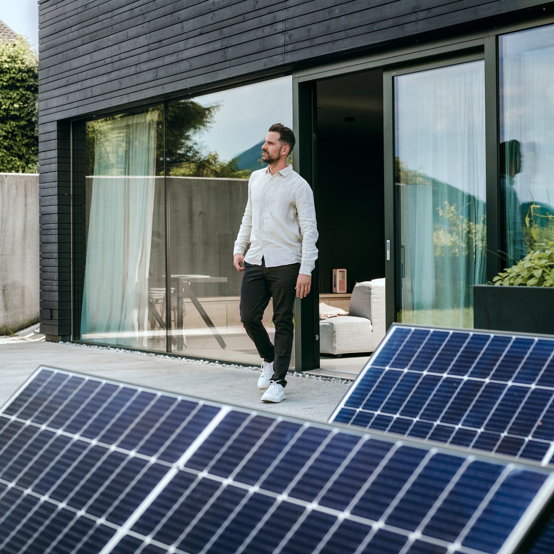 Mann vor Haus mit PV-Anlage im Vordergrund