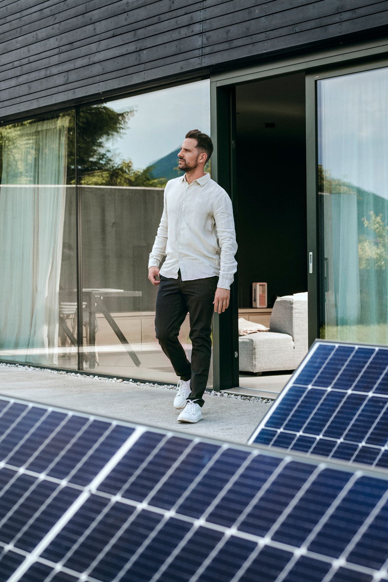 Mann vor Haus mit PV-Anlage im Vordergrund