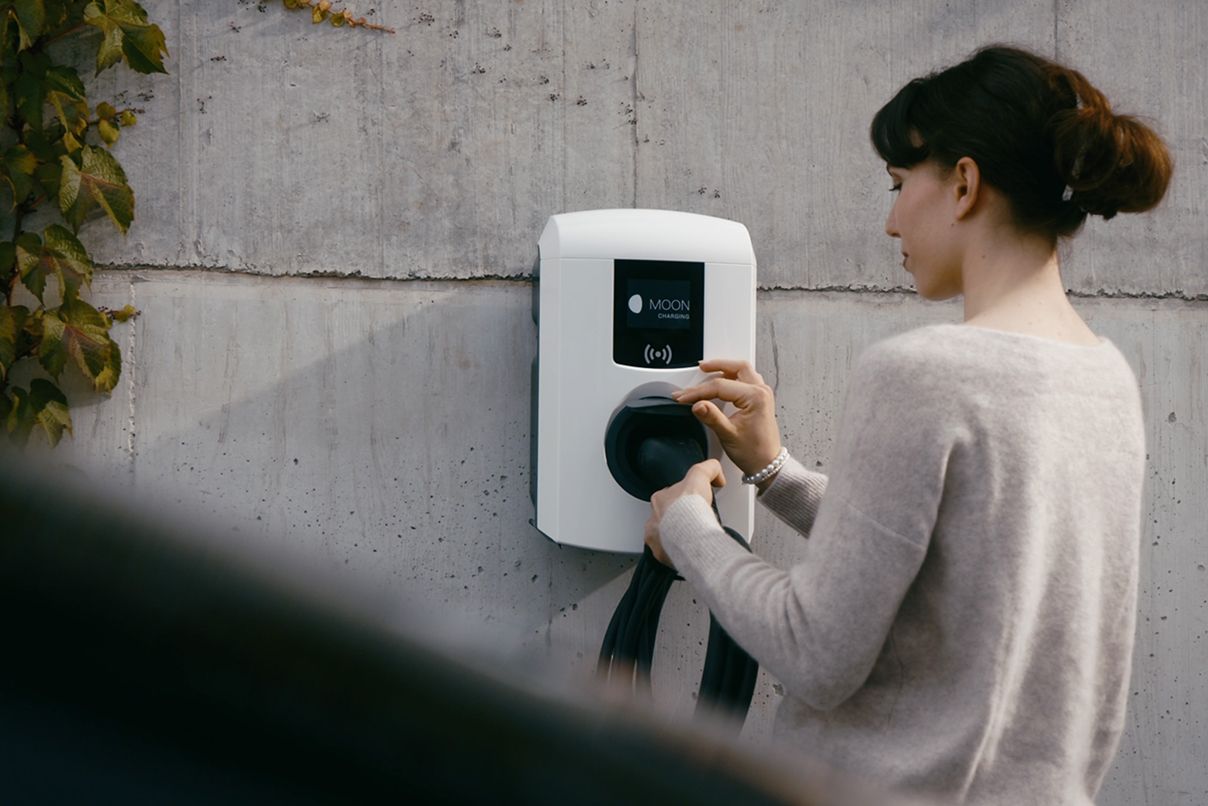 Frau steckt Kabel in eine Wallbox  